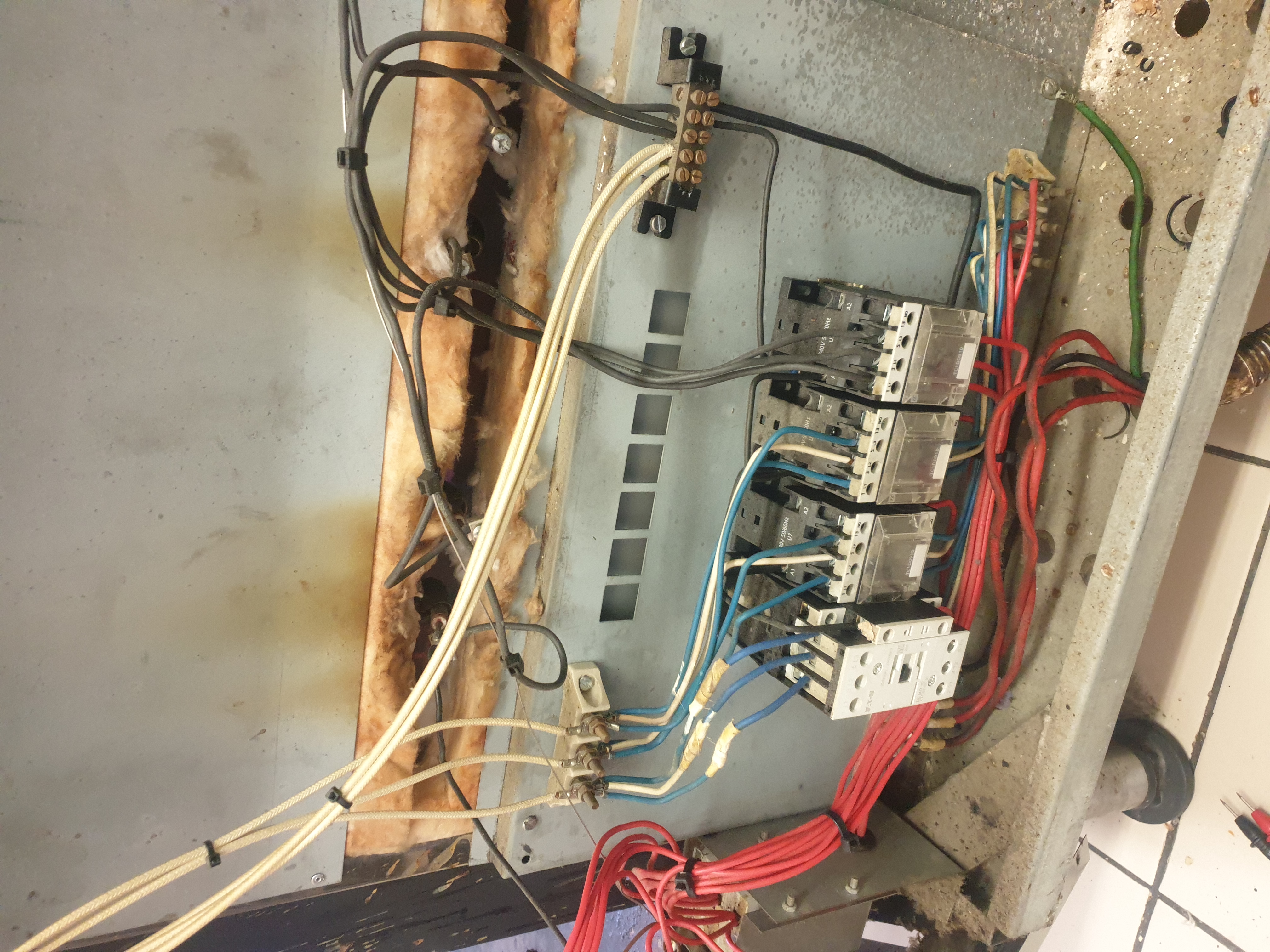Commercial stove wiring compartment with contactors and heat-aged wiring exposed