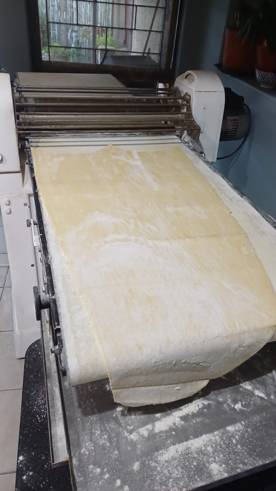Commercial dough sheeter with pastry dough running over the conveyor belt during service