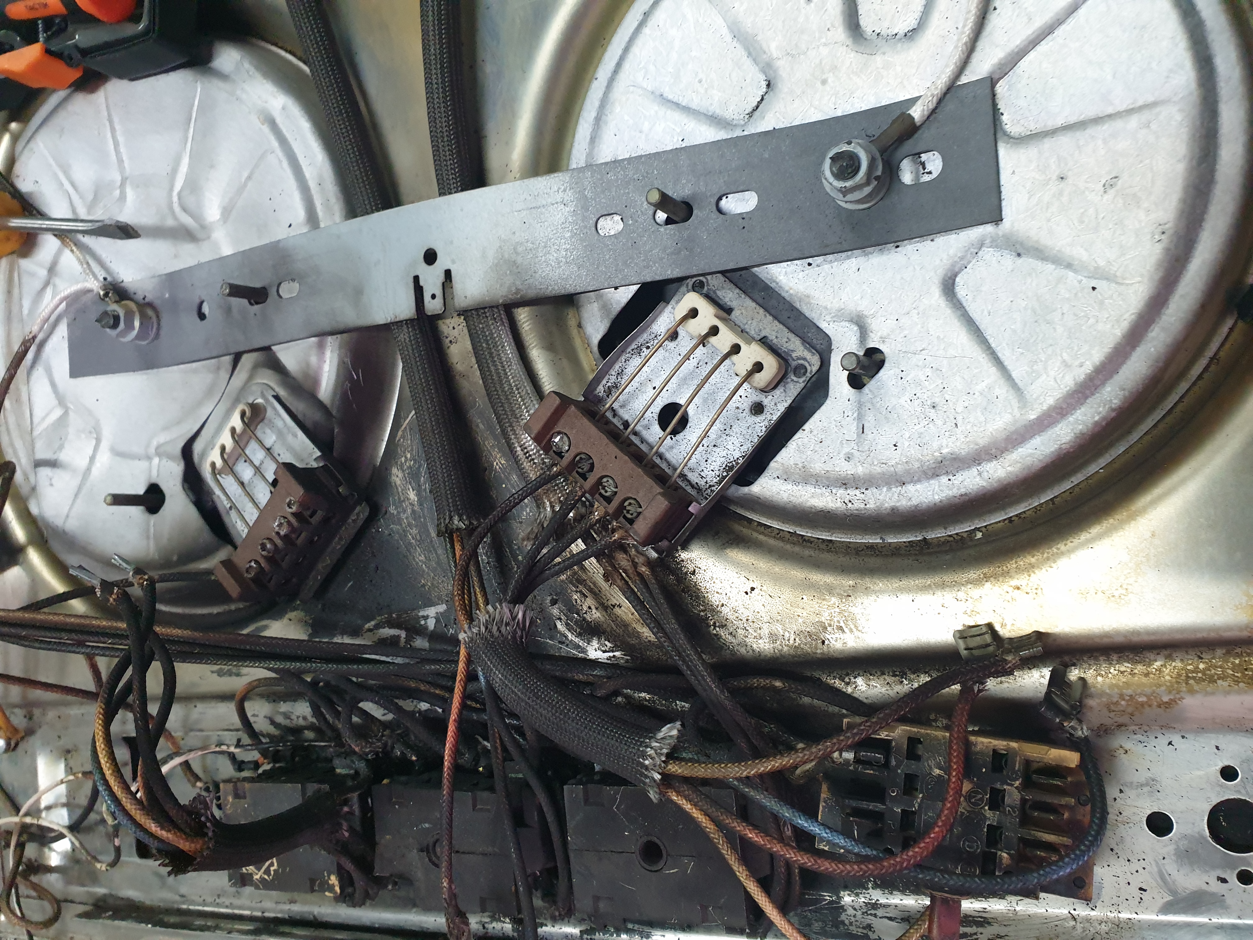 Commercial hotplate underside with heat-stressed wiring and ceramic terminal blocks