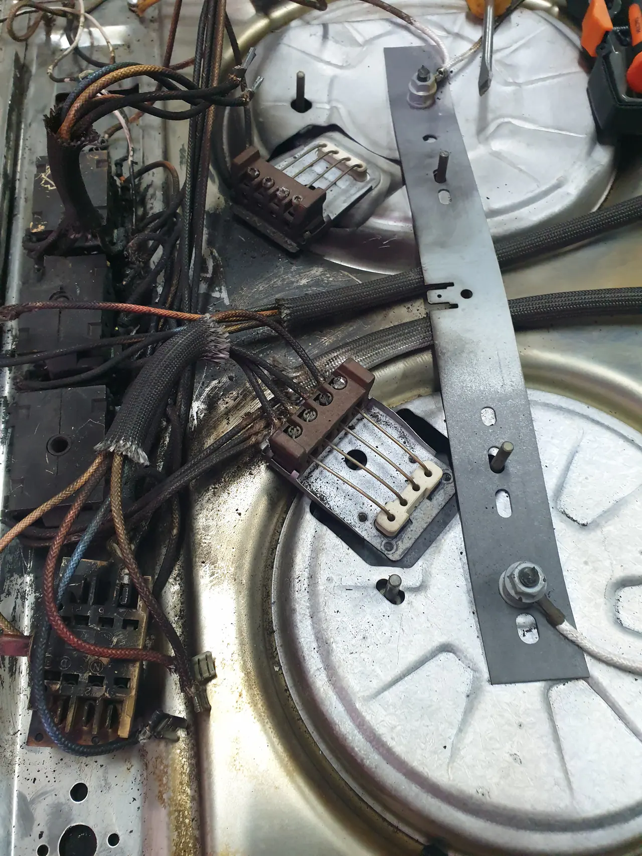 Commercial hotplate underside with heat-stressed wiring and ceramic terminal blocks